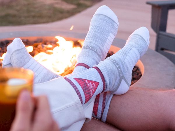 Two people snuggle with cozy socks by the outdoor fire pit