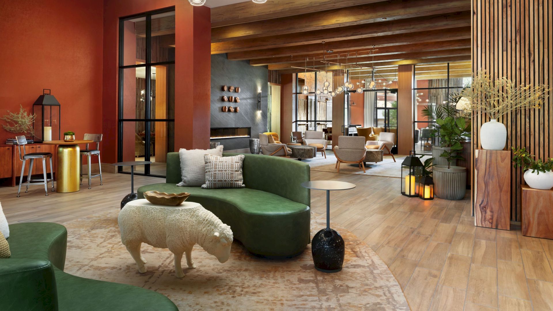 A modern interior with green couches, a sheep-shaped stool, wooden flooring, orange and wooden accents, and stylish lighting.