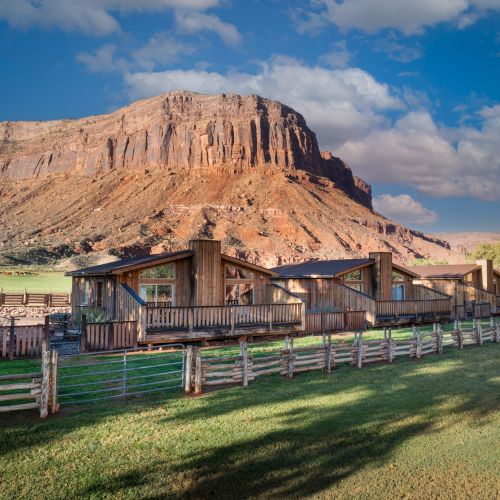A rural village with thatched huts along a dirt road under blue skies and green paddies, capturing simple, rustic life.