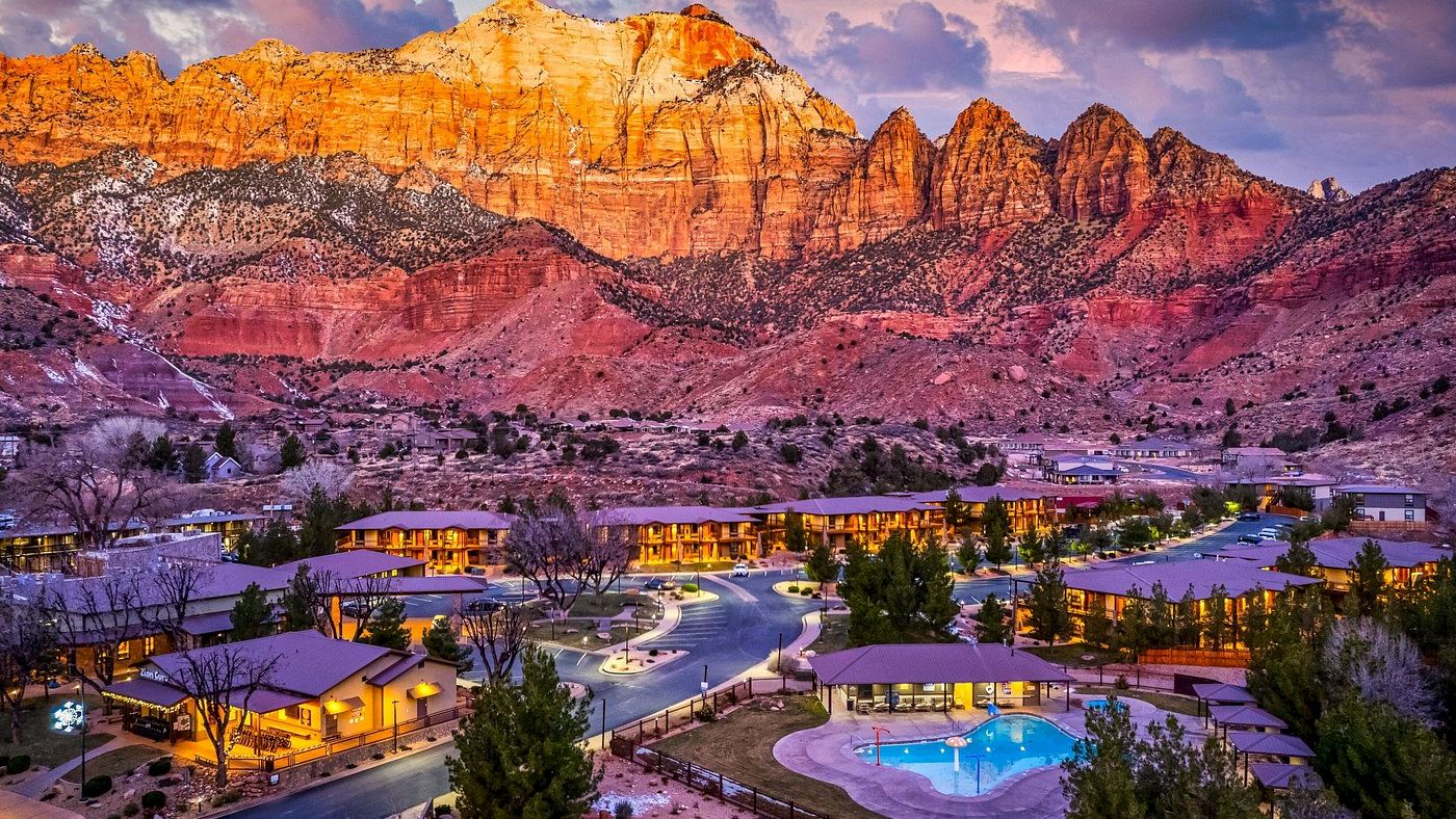Scenic view of a resort nestled in a desert landscape, with rugged mountains in the background and a pool area in the foreground.