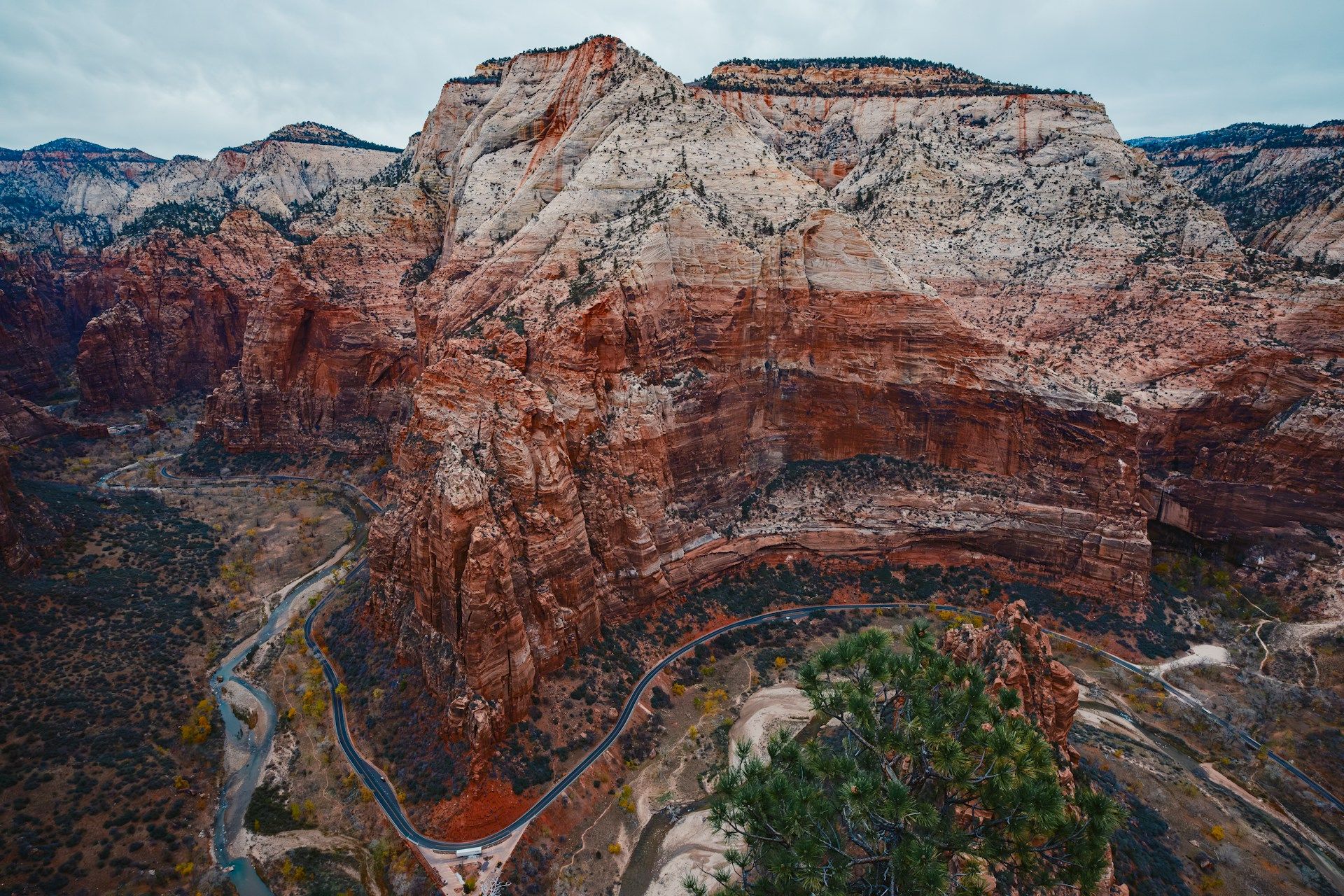 The image shows a scenic view of a winding road through a mountainous canyon with layered rock formations and sparse vegetation.