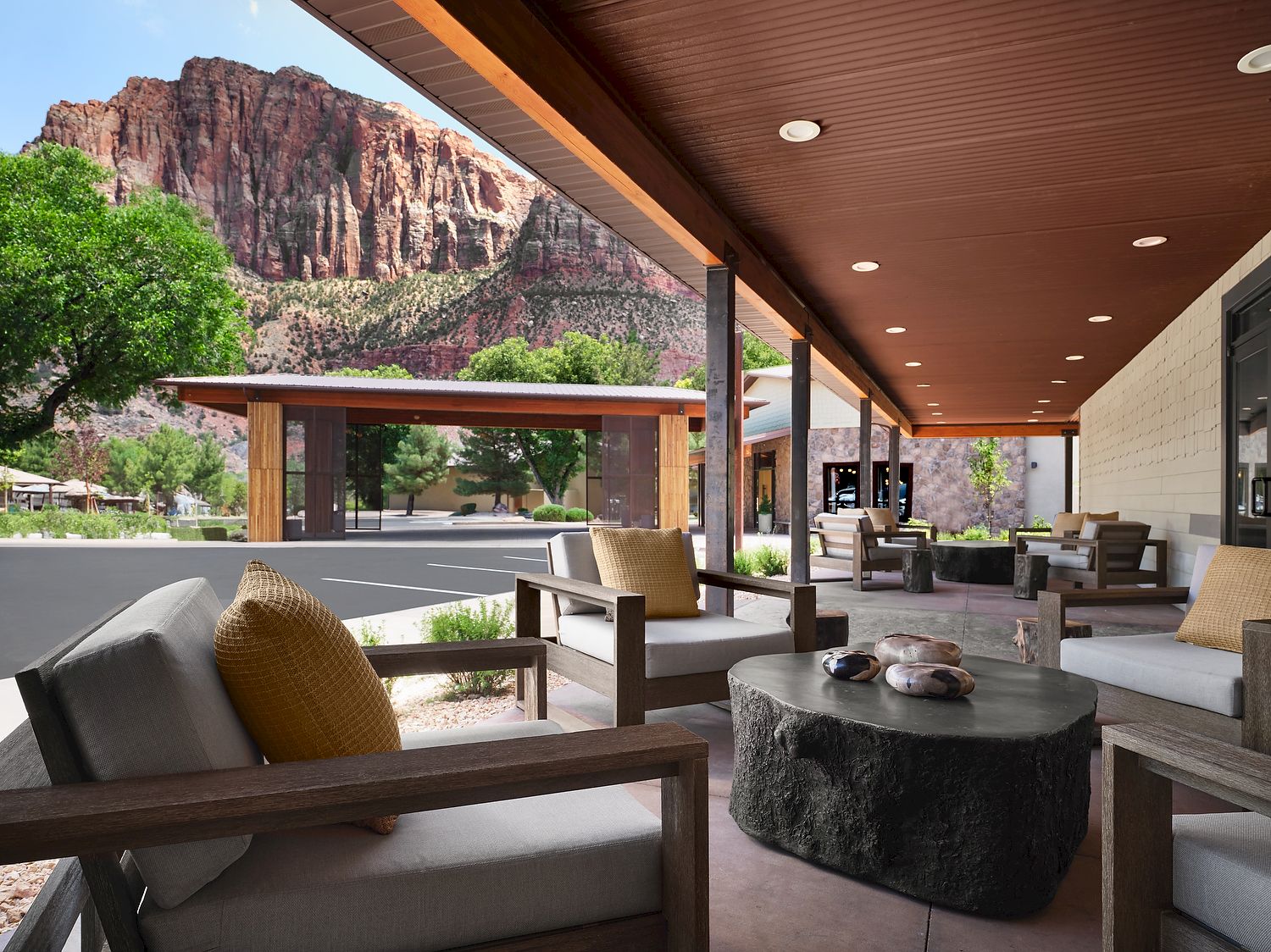 A covered patio with seating, a stone table, and a view of red rock cliffs and greenery outside.