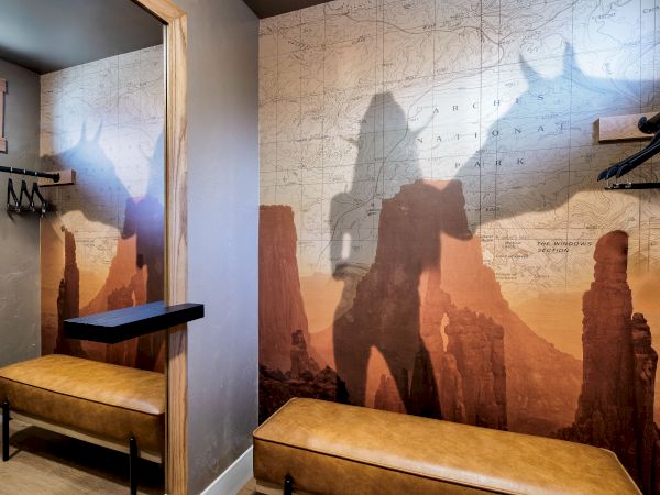A hallway with a desert canyon mural, benches, a coat rack, and a small window; the art features rock formations and warm sunset hues.